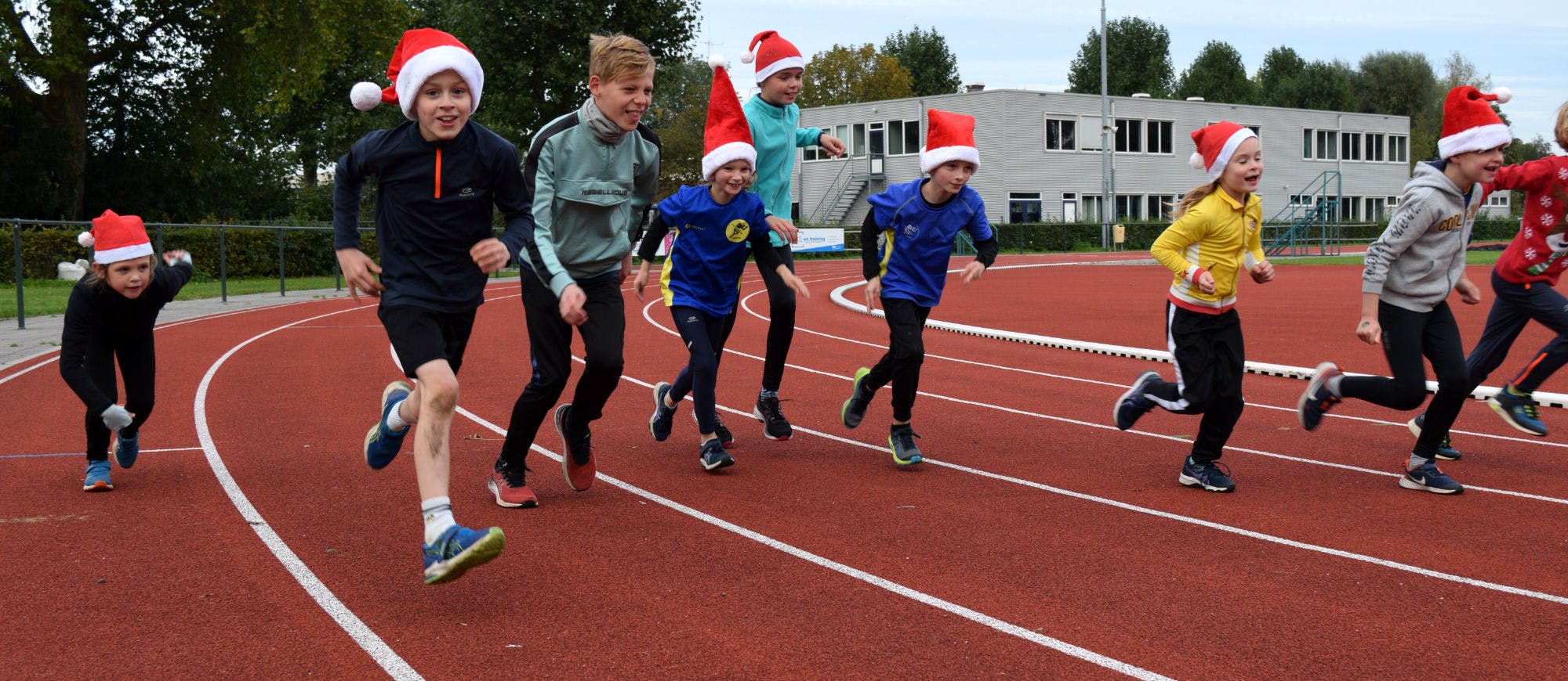 Kinderen in kerstoutfit op de atletiekbaan van Flevo Delta